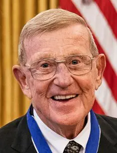 A man with glasses and a medal around his neck.