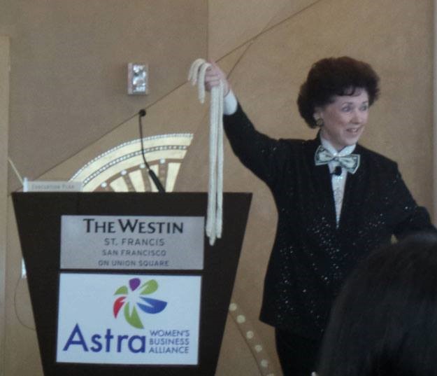 A woman in black jacket holding up a white ribbon.