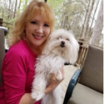 A woman holding a small white dog on her lap.